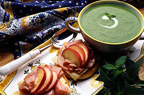 BAYS TOPPED WITH APPLE AND MEAT NEXT TO A GREEN BISQUE