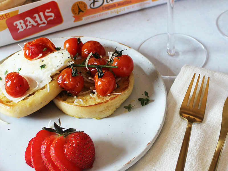 Cooked tomatoes topping bays on a white marble countertop with bronze silverware