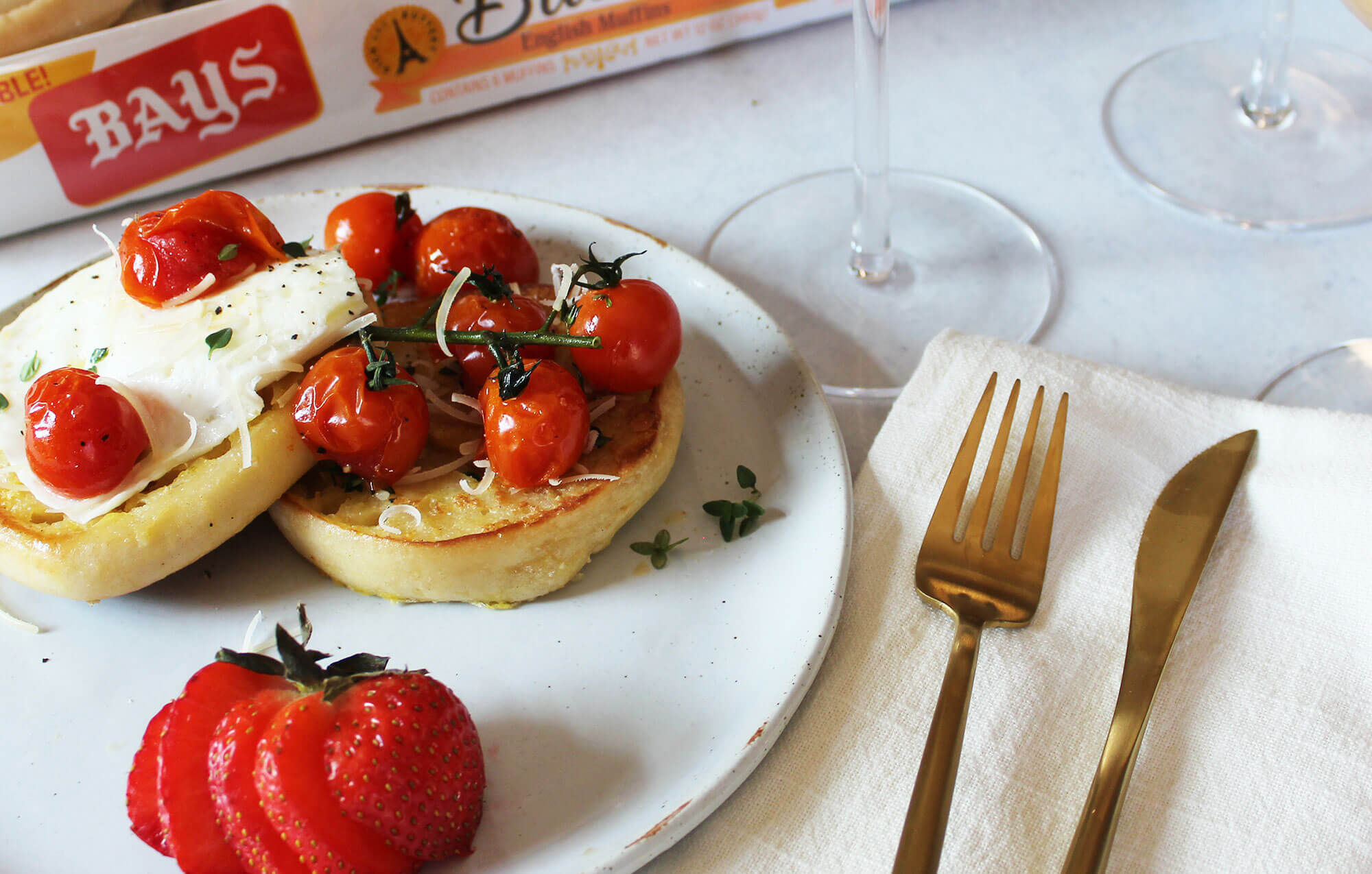 Cooked tomatoes topping bays on a white marble countertop with bronze silverware